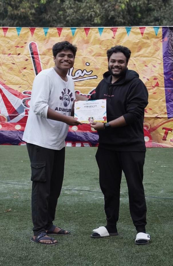 Two people posing together outdoors while presenting a certificate