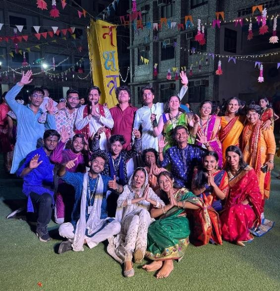 Group photo at an evening gathering with string lights and colorful traditional outfits