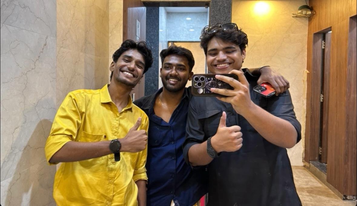 Friends posing together indoors, giving a thumbs up